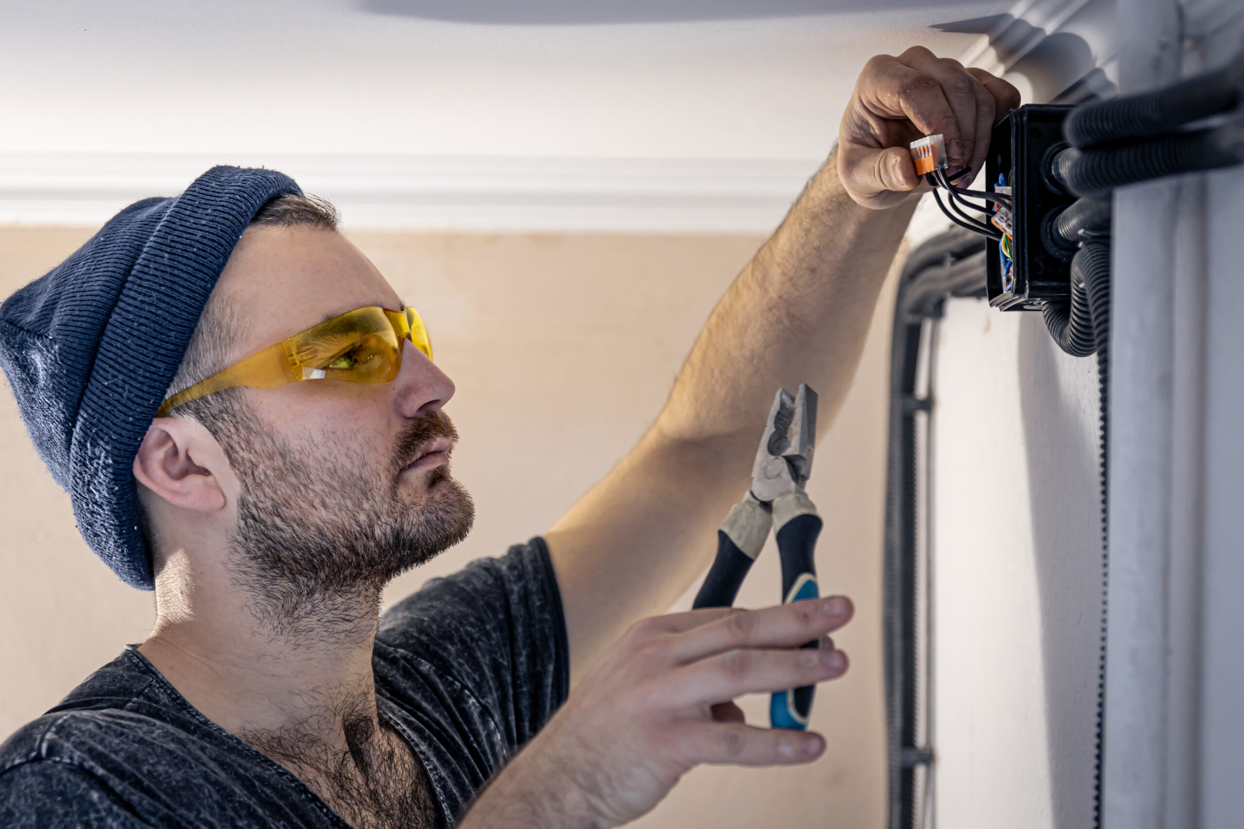 An electrician is mounting electric sockets on the white wall indoors.